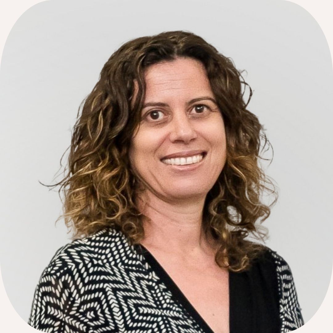 Headshot of Annie Pettit who has short, curly hair and wears a patterned, black top.