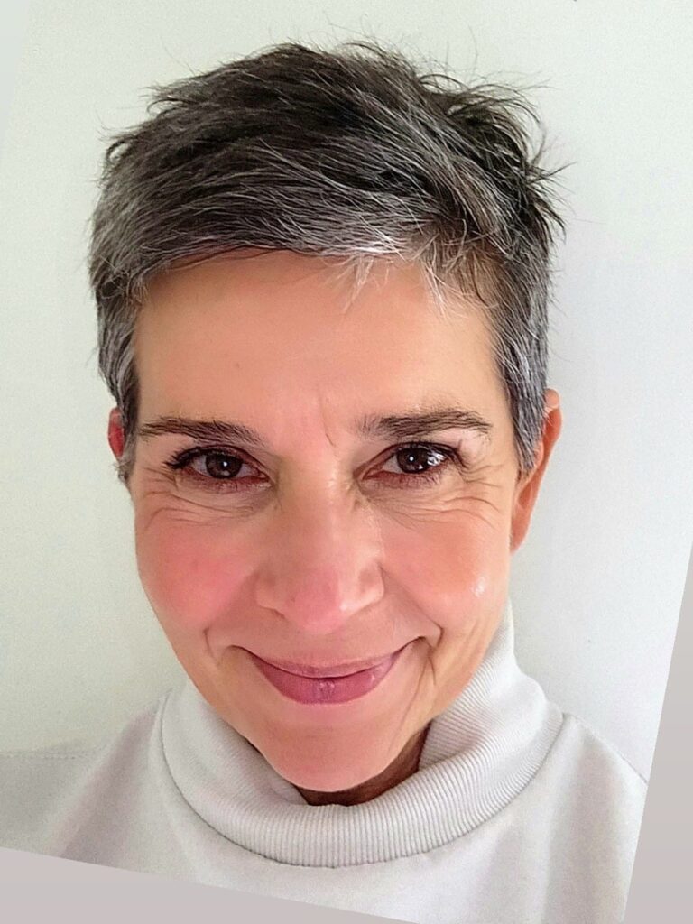Headshot of Elena Katrakis. Elena has short, grey hair and a white polo neck shirt.