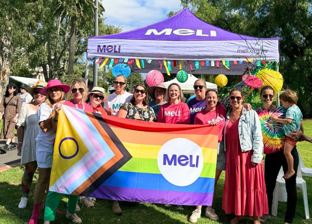 Meli employees celebrating Pride. A group of people holding a Pride flag with the word Meli written on it.