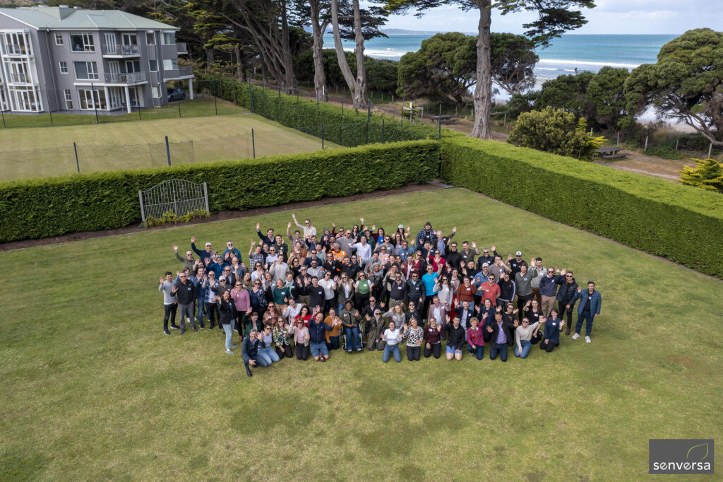 Large group of people standing together on a lawn for a team photo.