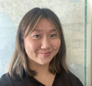 Deborah Wu, a person with shoulder length brown hair wearing a black shirt smiling at the camera.