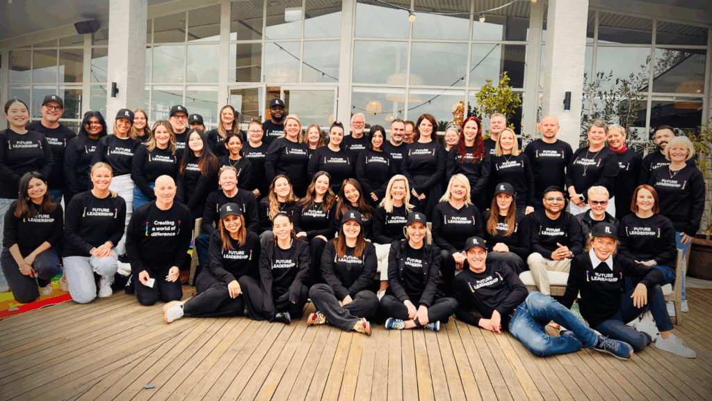 Group of people smiling in a group photo, all wearing the same uniform.