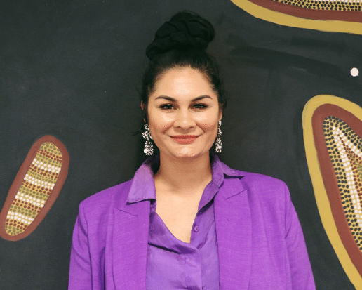 Jordin Payne wearing a purple blazer and purple top and has her hair up in the bun.
