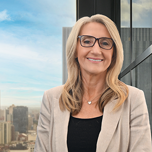 Portrait image of Zana Bytheway. She has long blonde hair, wears glasses and is wearing a black t-shirt with a cream jacket over it.