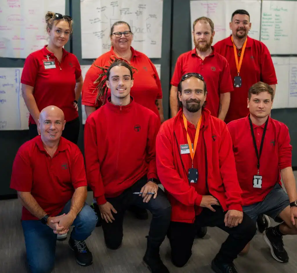 A group of Bunnings employees stand together and pose and smile at the camera